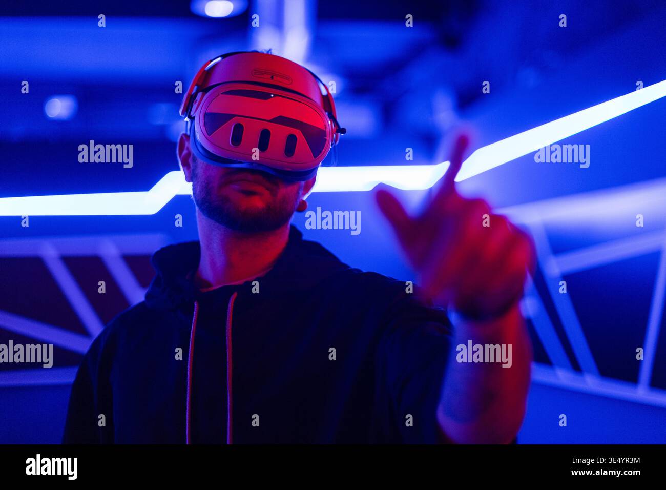 Coole Techniker mit VR-Headset-Brille steuert virtuelles Menü in dunklen Räumen mit Neonlicht Stockfoto