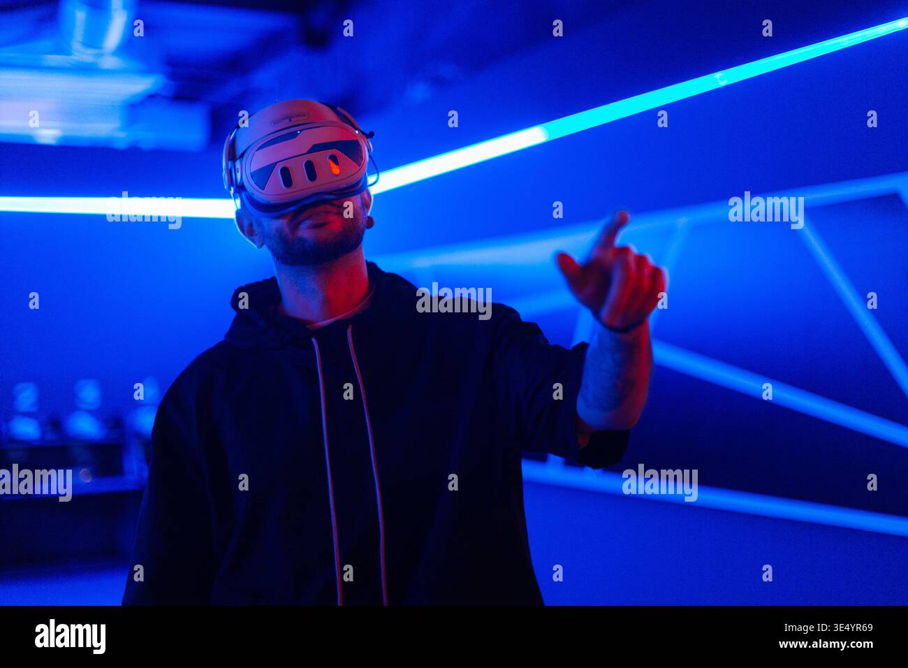 Coole Techniker mit VR-Headset-Brille steuert virtuelles Menü und berührt mit dem Finger in dunklen Räumen mit Neonlicht Stockfoto