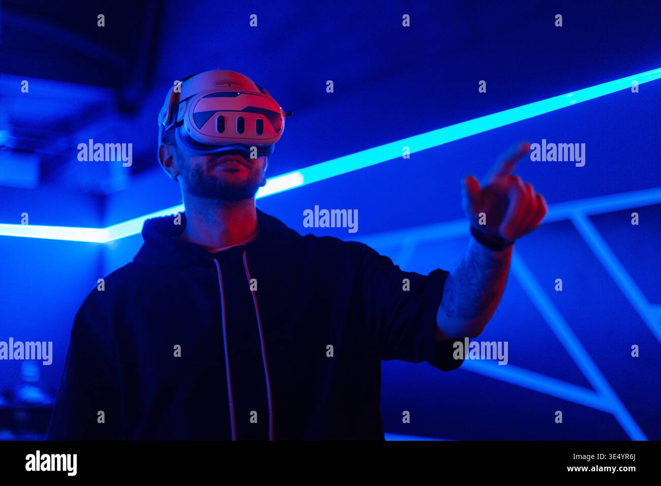 Cyber ​​man mit VR-Brille verwendet das Headset und streichelt den Finger in die virtuelle Welt in dunklen Räumen mit Neonlicht Stockfoto