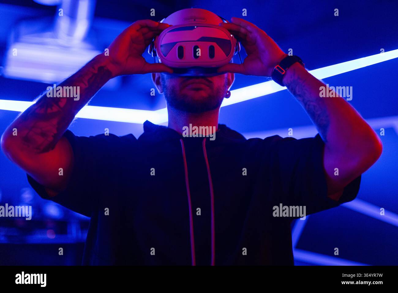 Mode-cooler Tech-Mann trägt moderne VR-Brillen in dunklen Räumen mit Neonlicht. Gamer in der virtuellen Welt Stockfoto