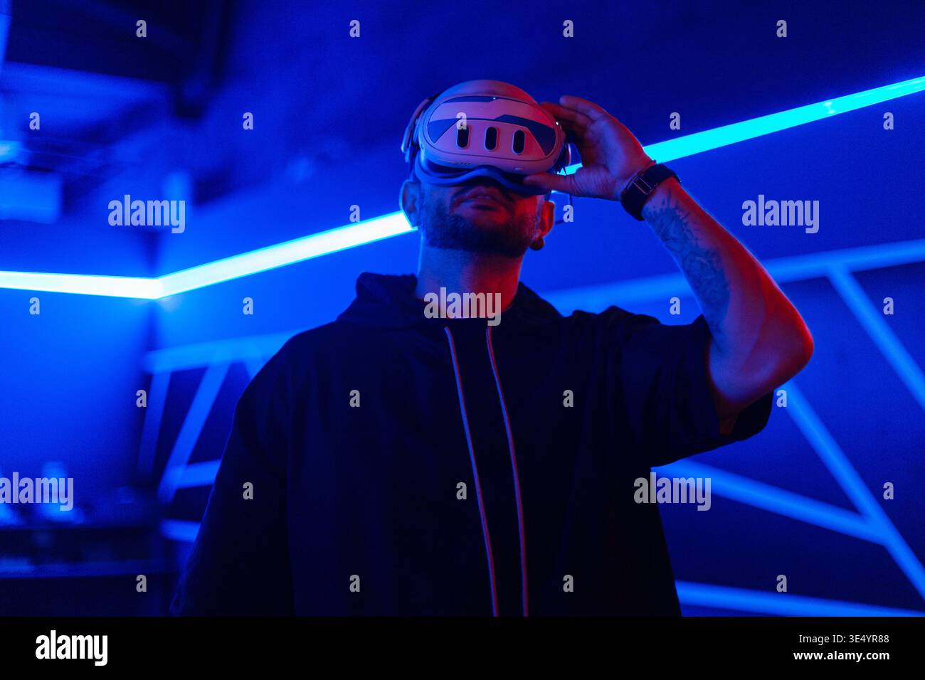 Cyber ​​man mit VR-Brille verwendet das Headset in der virtuellen Welt in dunklen Räumen mit Neonlicht Stockfoto