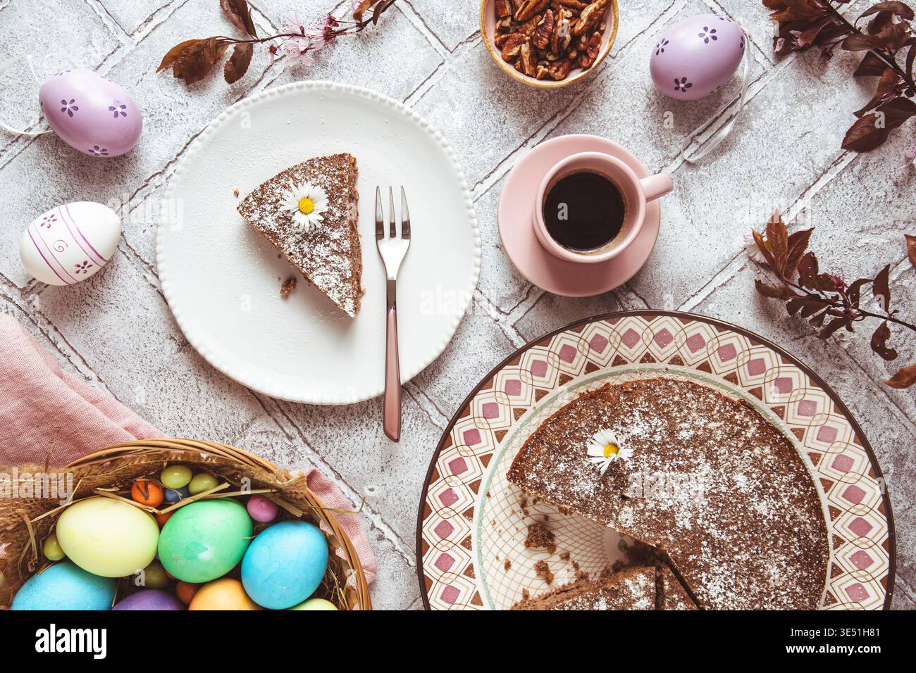 Ein Stück Nusskuchen auf einem Teller und farbige ostereier auf dem ostertisch. Low Carb, Keto, Diät. Draufsicht. Stockfoto