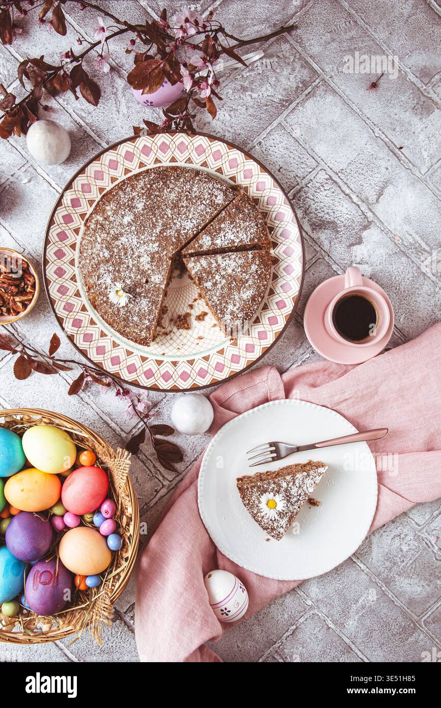 Ein Stück Nusskuchen auf einem Teller und farbige ostereier auf dem ostertisch. Low Carb, Keto, Diät. Draufsicht. Stockfoto