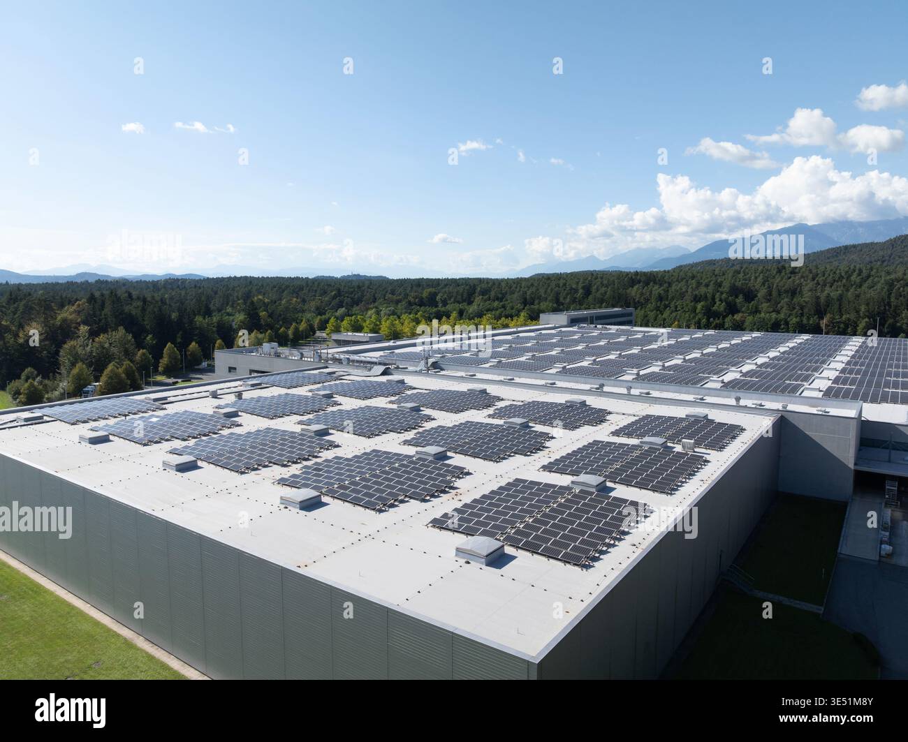 Luftaufnahmen zeigen Solarpaneele, die in einem Gebäude installiert sind und die Erzeugung erneuerbarer Energien an einem klaren Himmel hervorheben. Stockfoto