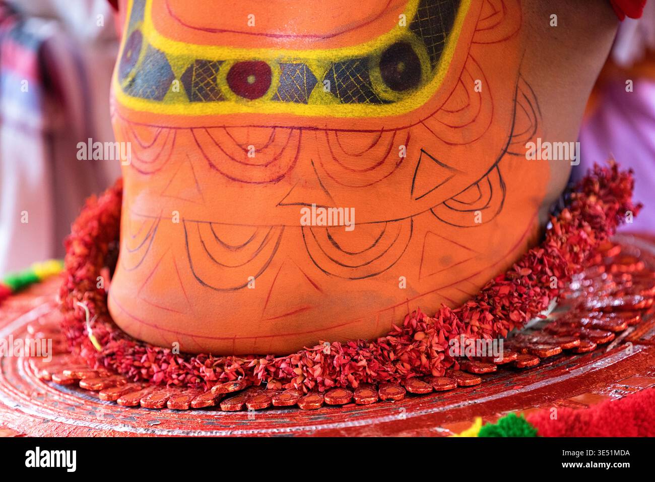 Nahaufnahme des aufwendigen traditionellen Kostüms, des farbenfrohen Gesichts Make-ups und des kunstvollen Kopfschmucks, den ein Theyyam-Künstler in Kannur, Indien, trägt Stockfoto