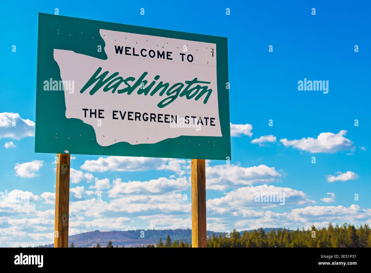 Ein Schild am Straßenrand mit Willkommen im Staat Washington, dem immergrünen Bundesstaat mit ländlicher Umgebung und blauem Himmel dahinter. Stockfoto