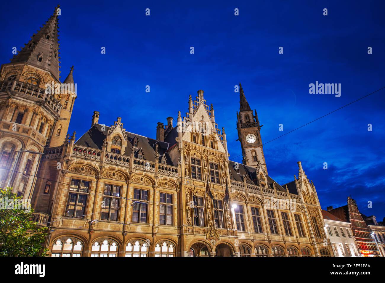 Abendblick auf das beleuchtete Hauptgebäude und den Uhrturm des Postgebäudes, der ehemaligen Post am Korenmarkt in Gent Belgien. Stockfoto