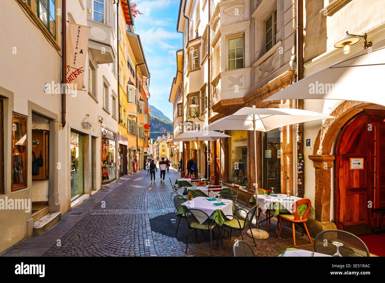 Eine enge Kopfsteinpflasterstraße mit Geschäften und Straßencafés in der historischen Altstadt von Bozen, Italien, in der Provinz Südtirol Stockfoto