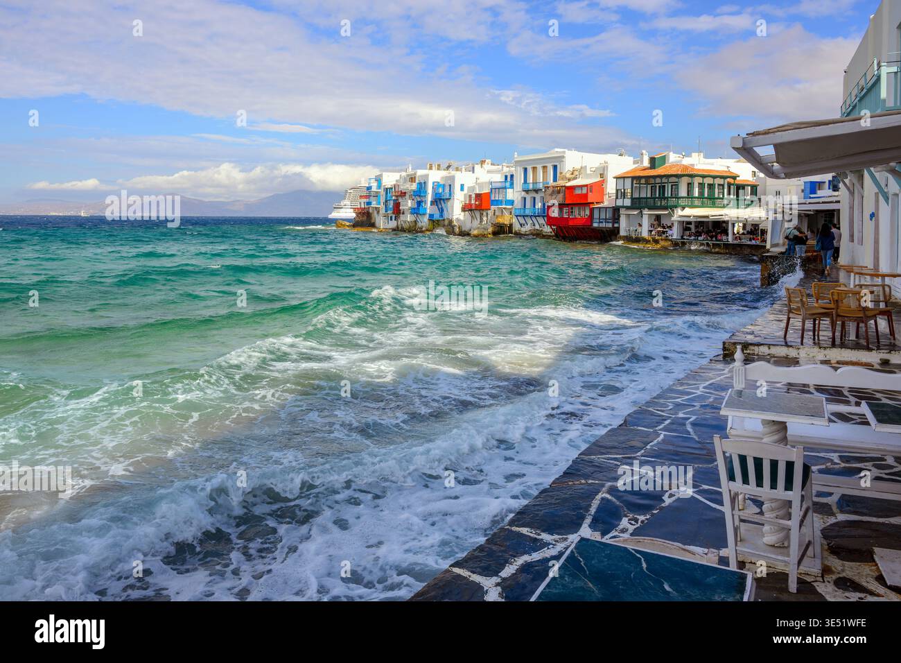 Wellen brechen gegen die Restaurants am Meer und die farbenfrohen Häuser aus dem 18. Jahrhundert im Viertel Little Venice in Mykonos Town auf der Insel Mykonos Griechenland Stockfoto