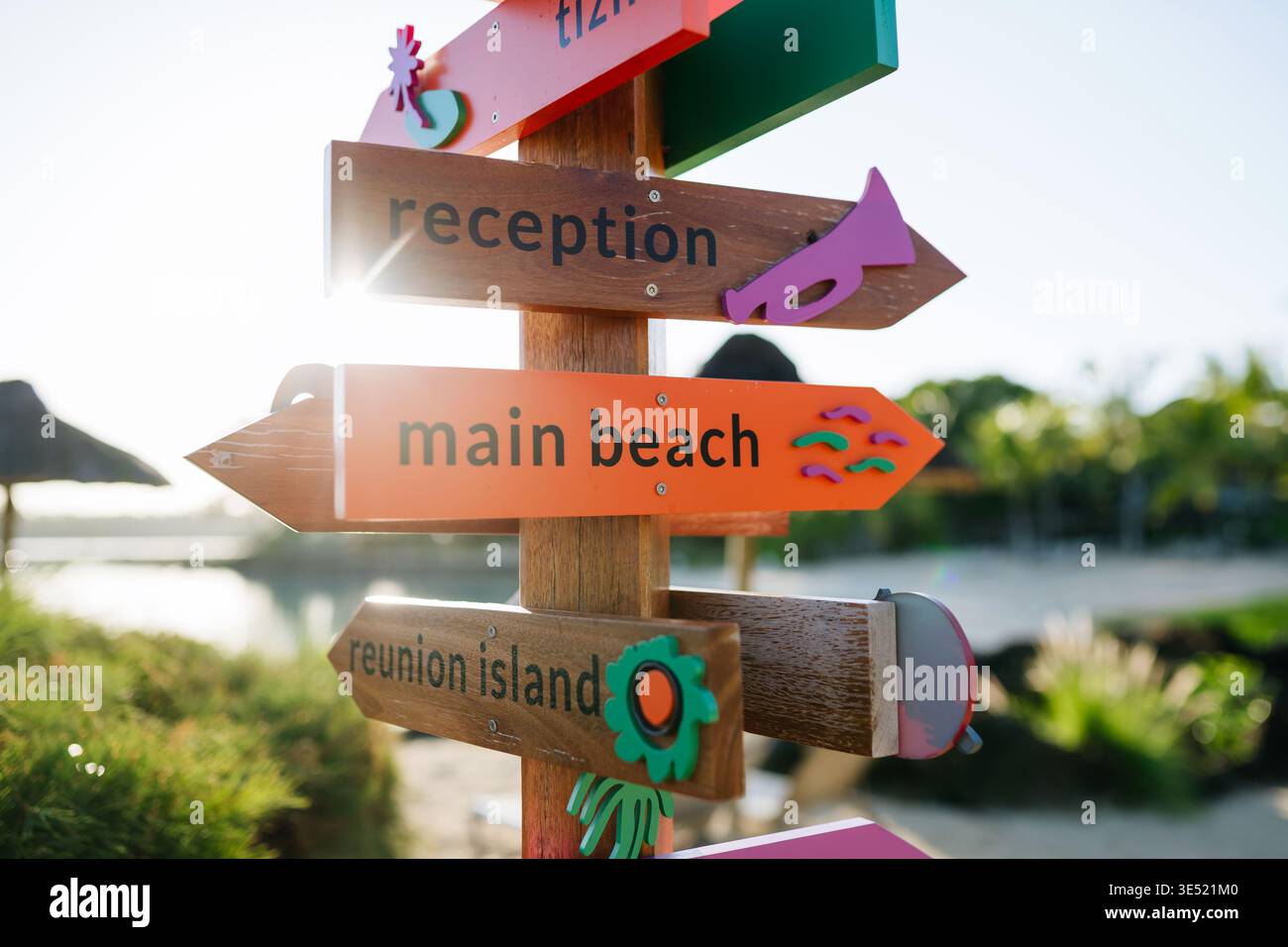Bunte hölzerne Richtungsschilder zeigen zum Strand und zur Rezeption im tropischen Resort. Stockfoto