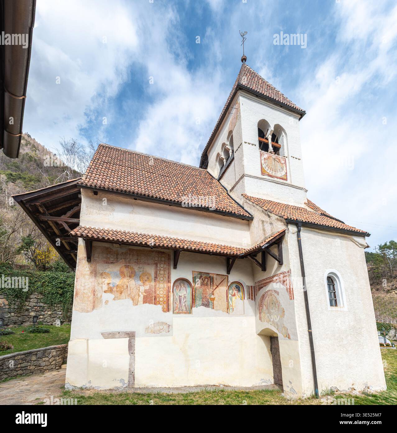 Antike romanische Kirche St. Peter in Tirol bei Meran, Südtirol, Italien, mit mittelalterlichen Fresken und alpinem Hintergrund Stockfoto