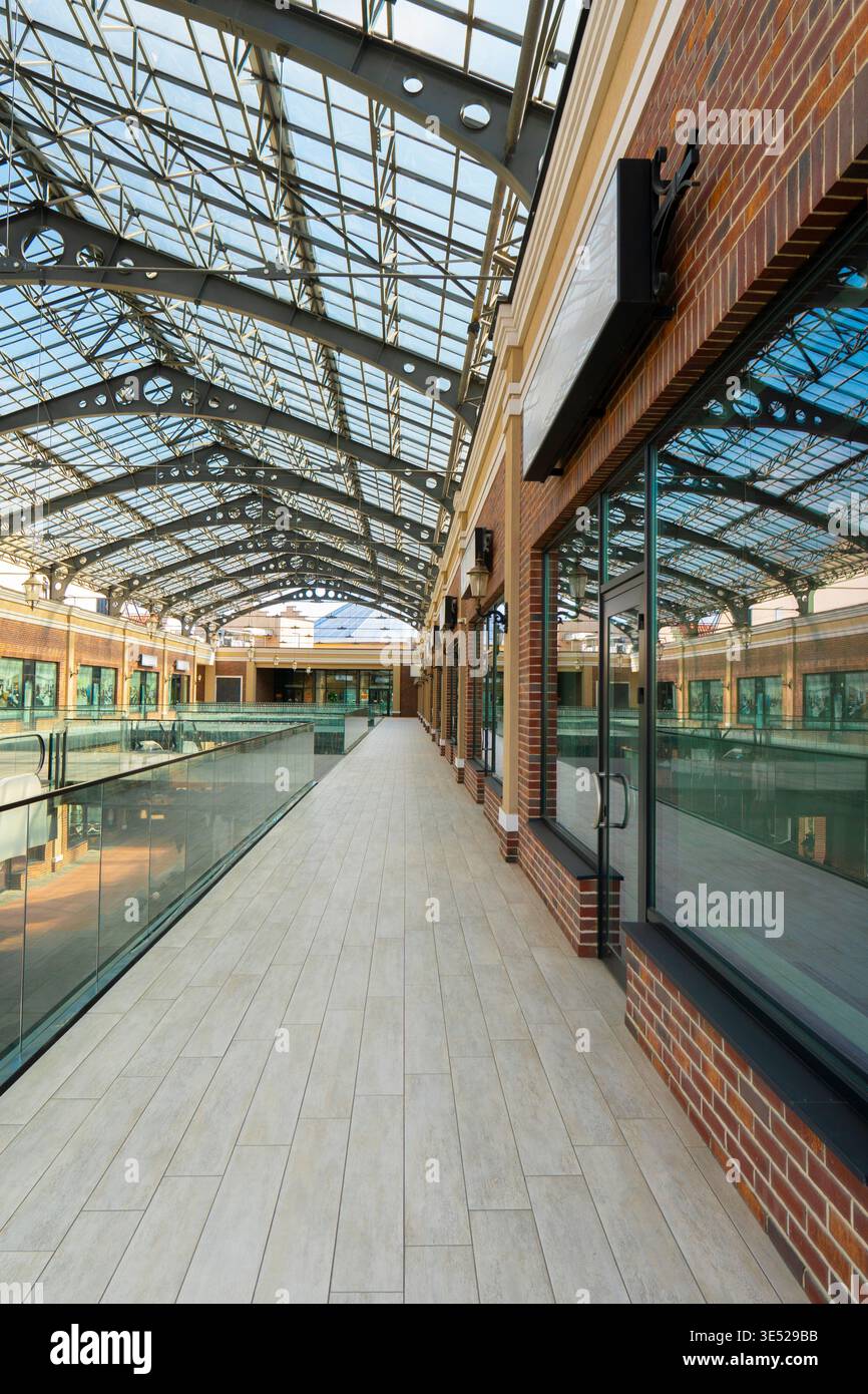 Innenansicht einer modernen Galerie mit großer Industrieglasdecke, Backsteinfassaden, Glasgeländern und hellem Fußboden Stockfoto