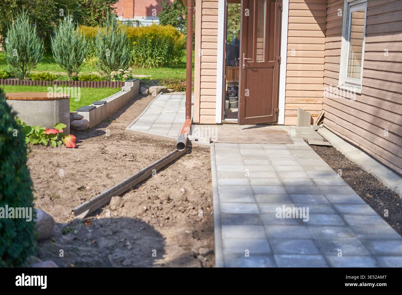 Ein hölzernes Wohnhaus außen mit hellbraunem horizontalen Abstellgleis und weißer Fensterverkleidung. Eine offene braune Holztür mit Glaspaneelen zeigt einen Stockfoto