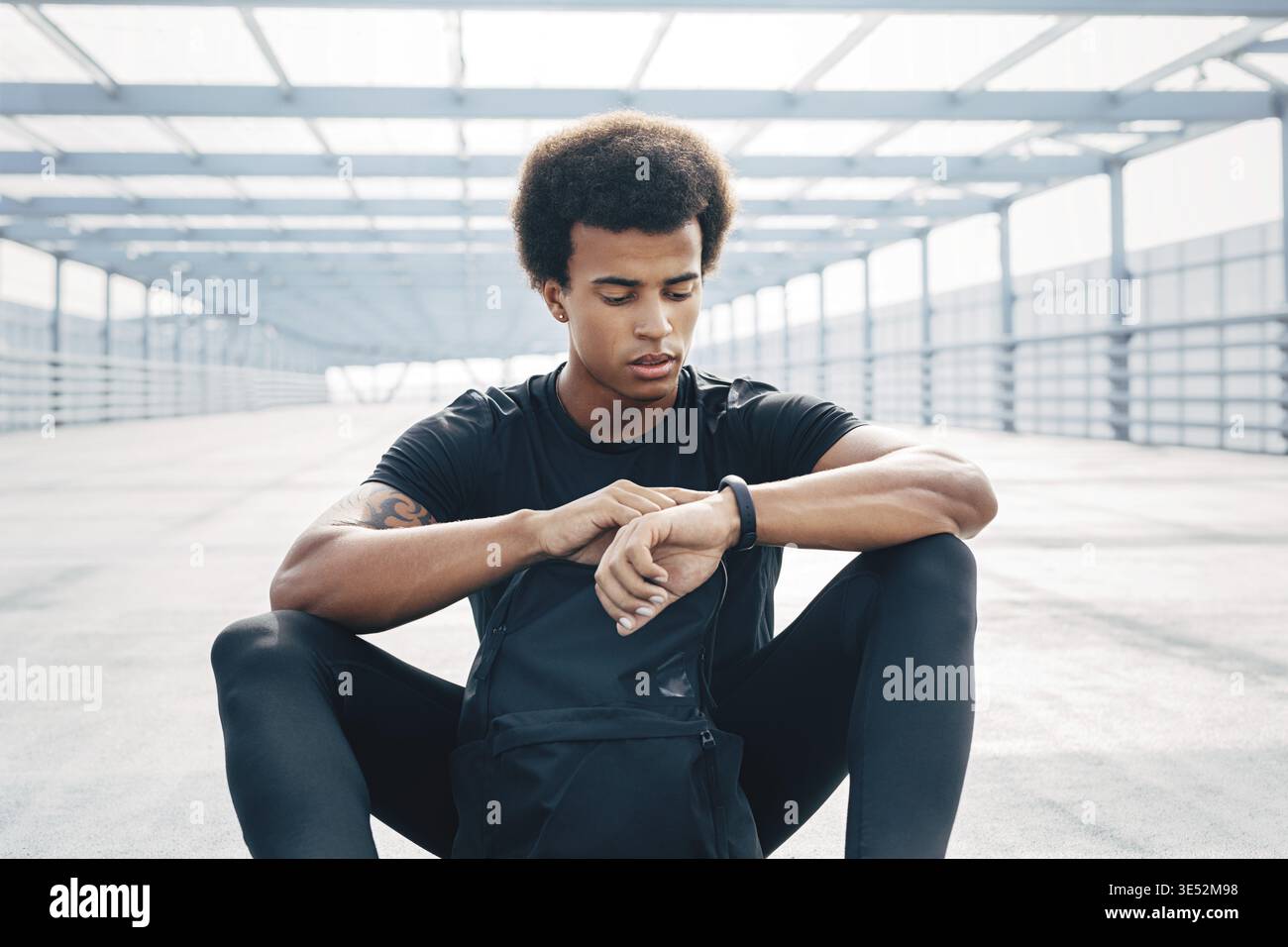 Junge Mann sitzt im Freien mit einem Fitness Tracker seine Fortschritte zu überwachen Stockfoto