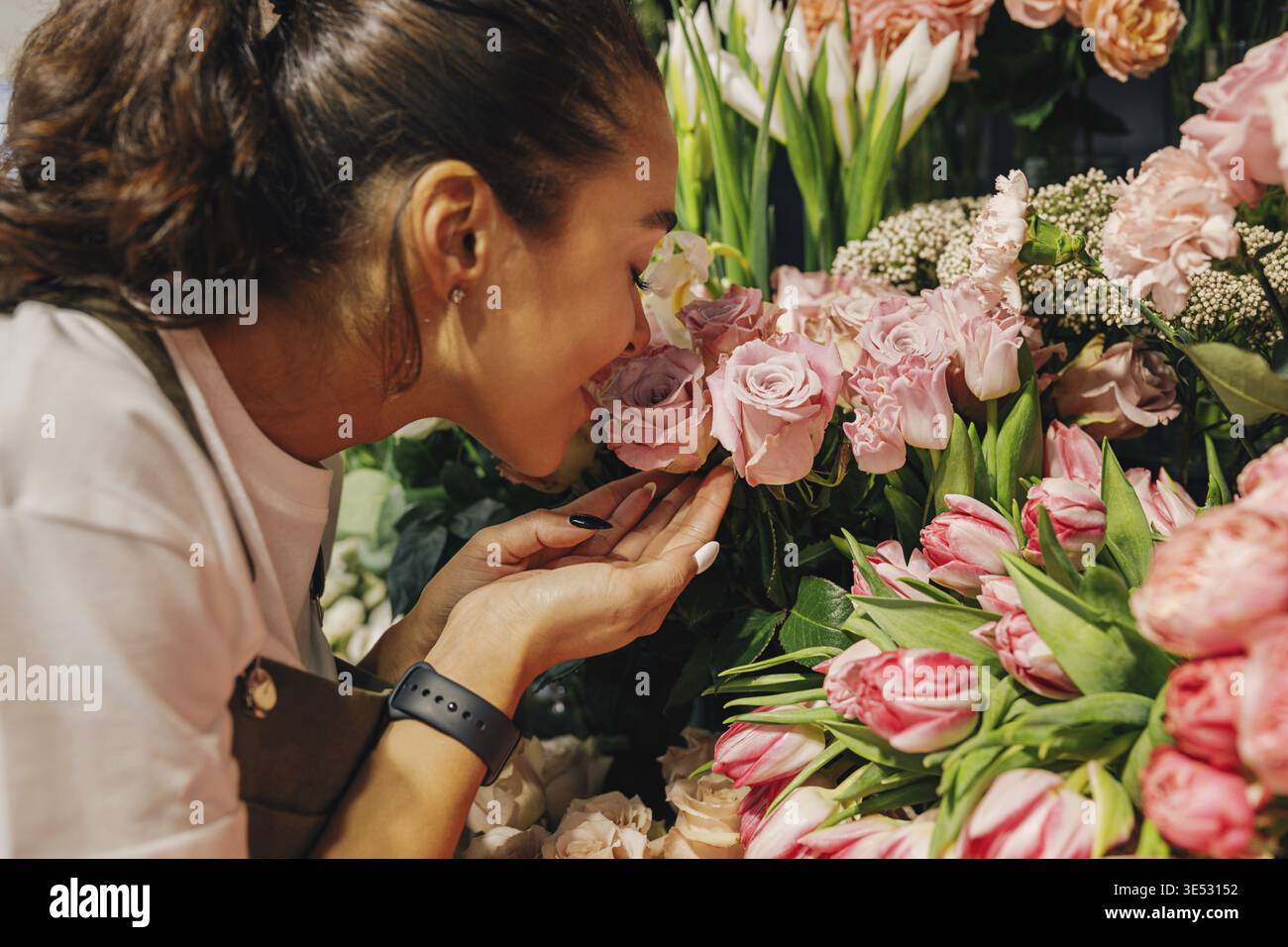 Nahaufnahme einer Frau, die im Blumenladen die Blumen riecht Stockfoto