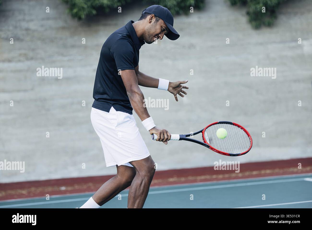 Junger Mann, der draußen Tennis spielt. Tennisspieler, der einen Ball schlägt Stockfoto