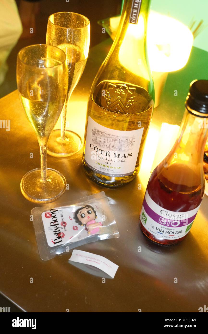 Eine Flasche Weißwein mit Gläsern, Rotweinessig und ein kleines Maskottchen auf einem Tisch Stockfoto