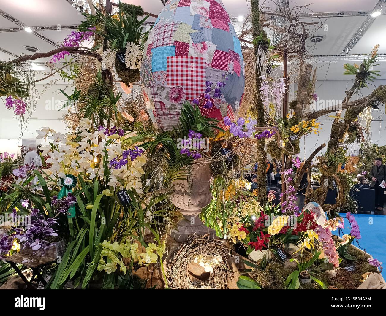 28. März 2026, Dresden, Deutschland: Großes Flickenteppich Ostereier-Herzstück umgeben von einer aufwendigen Ausstellung blühender Orchideen und tropischer Pl Stockfoto