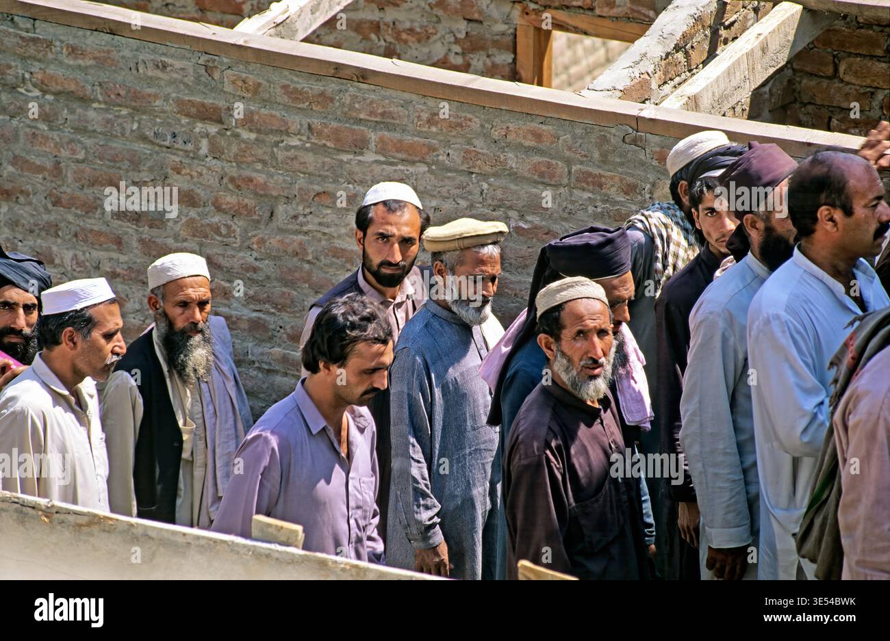 Gruppen von Männern gehen zusammen in Peshawar. Sie bewegen sich früh am Tag auf ihre Arbeit zu. Die Szene zeigt das tägliche Leben in der Stadt. Stockfoto