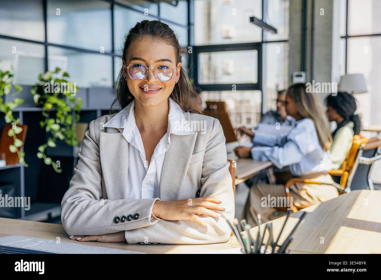 Der kaukasische Marketingchef zeigt ein warmes Lächeln mit überkreuzten Armen Stockfoto