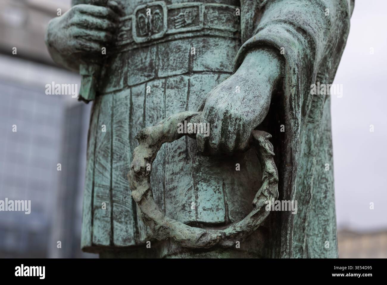 Nahaufnahme einer verwitterten Bronzestatue, die einen Lorbeerkranz hält, mit komplizierten Texturen, oxidierter Patina und klassischer römischer Militärkleidung Stockfoto