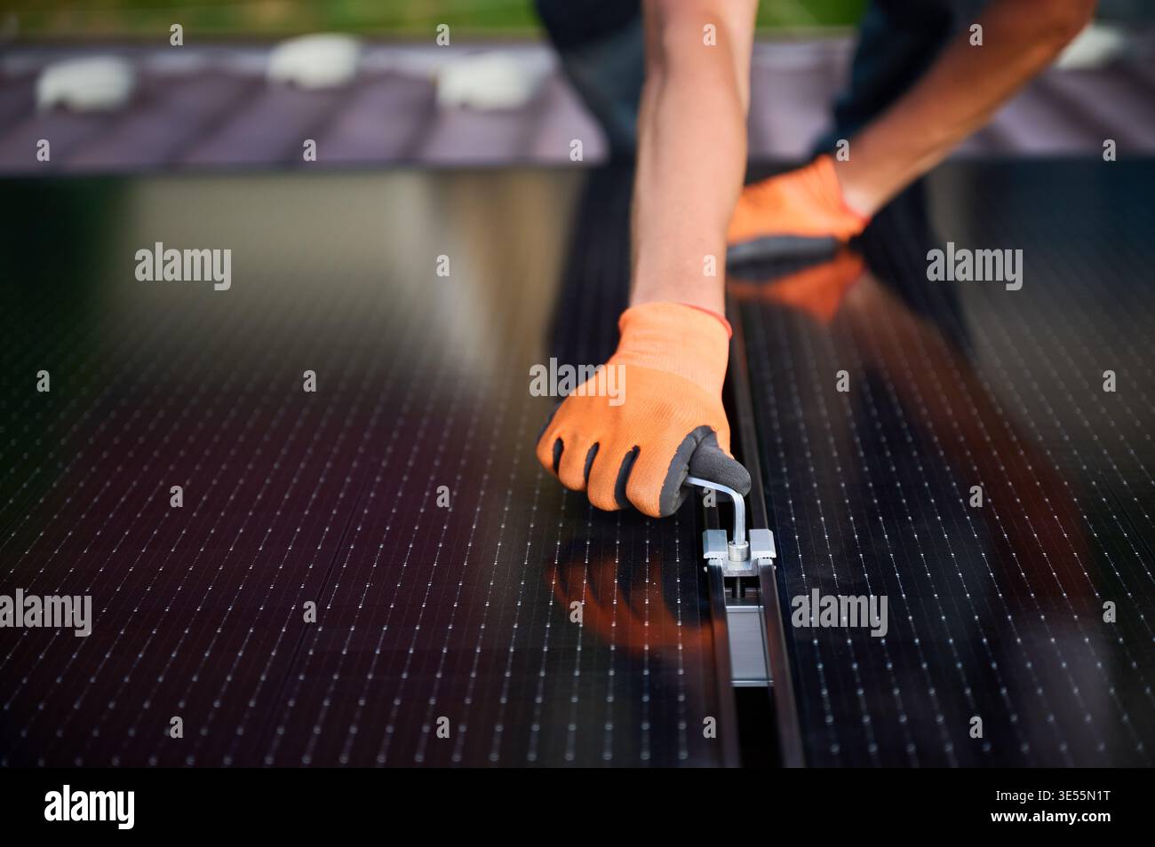 Arbeiter, der eine Photovoltaik-Solarpaneel-Anlage auf dem Dach des Hauses baut. Nahaufnahme von man Ingenieur in Handschuhen, die Solarmodul mit Hilfe eines Sechskantschlüssels im Freien installieren. Konzept der Erzeugung erneuerbarer Energien. Stockfoto