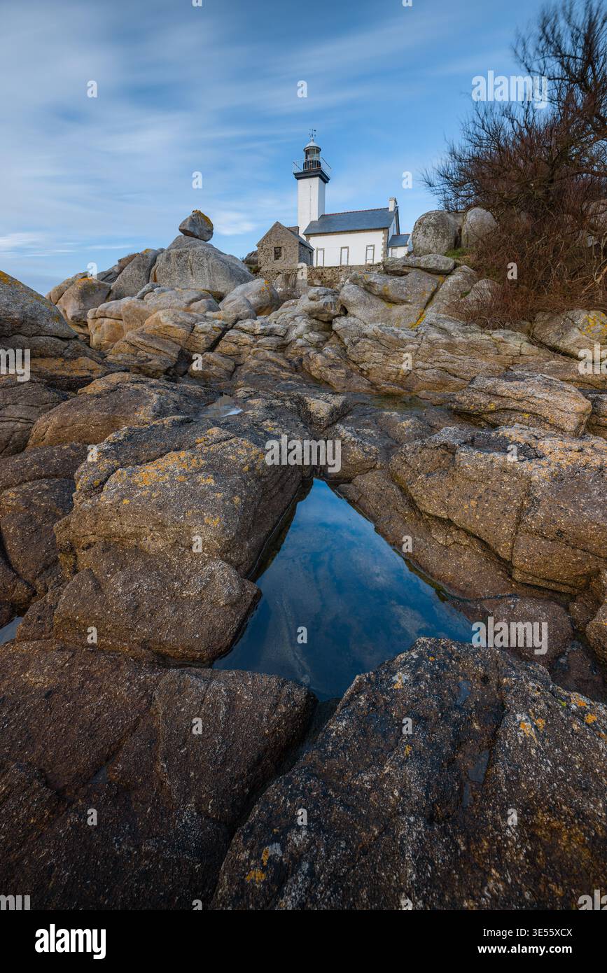 Blick auf den Leuchtturm von Phare de Pontusval, der auf Granitfelsen steht, mit einer Wasserspiegelung unter einem blauen Himmel in Plouneour-Brignogan-plages, Bretagne, Fran Stockfoto