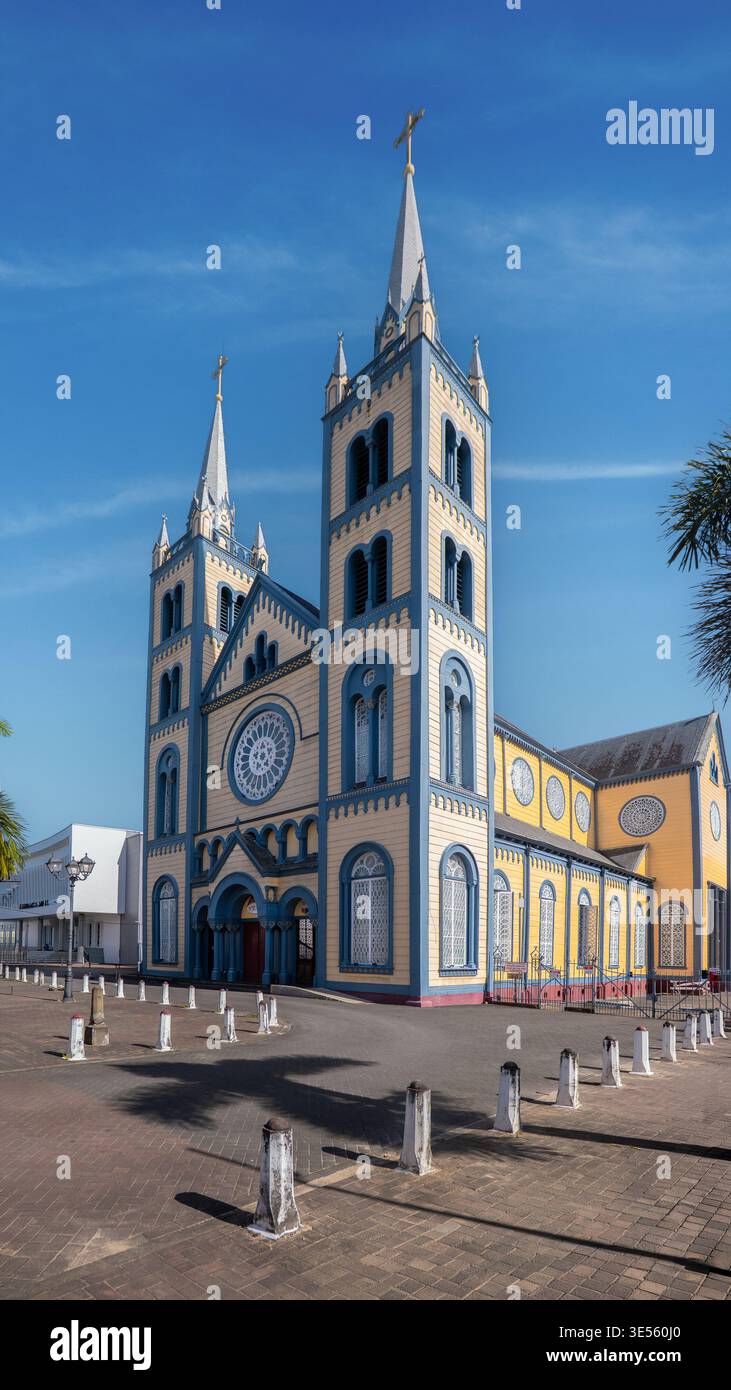 Blick auf die St. Peter und Paul Kathedrale mit ihrer ikonischen gelb-blauen Holzfassade und zwei Türmen unter einem klaren blauen Himmel in Paramaribo, Paramar Stockfoto