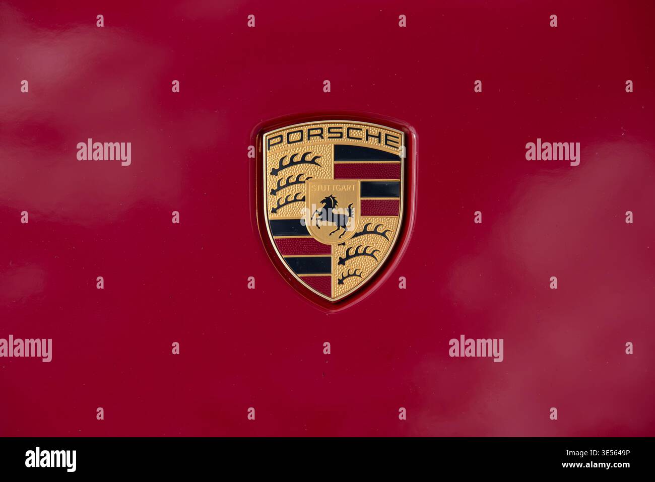 Valmiera, Lettland, 26. April 2025 – Nahaufnahme eines goldenen Porsche-Emblems auf einer glänzend roten Motorhaube mit dem ikonischen Logo der Luxussportwagenmarke. Stockfoto