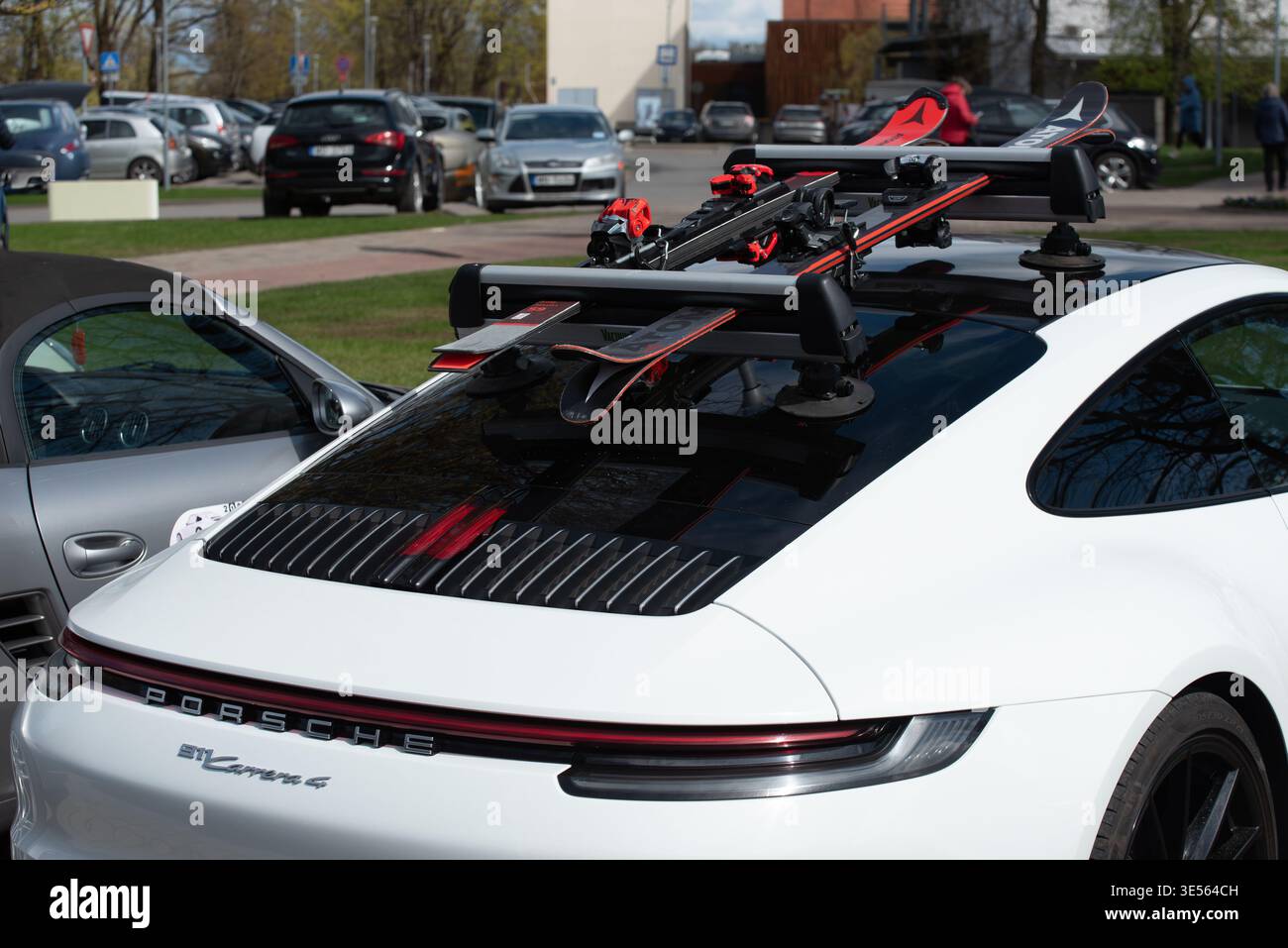 Valmiera, Lettland-26. April 2025-Weißer Porsche Carrera 4 mit Skiträger und Skiern auf dem Dach, während der Wintersportsaison im Freien geparkt. Stockfoto