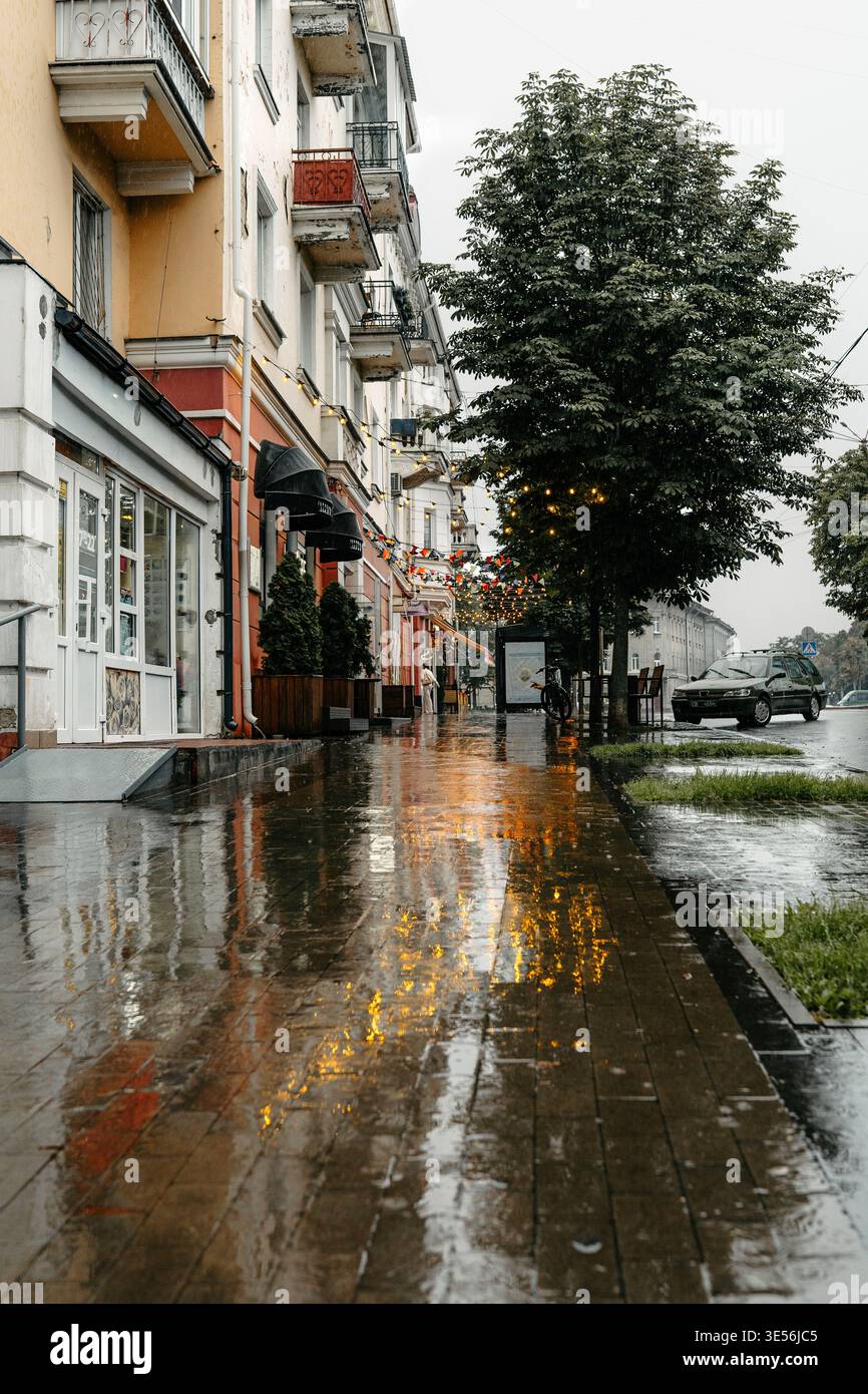 Rainy City Street mit Reflektionen und warmen Lichtern Stockfoto