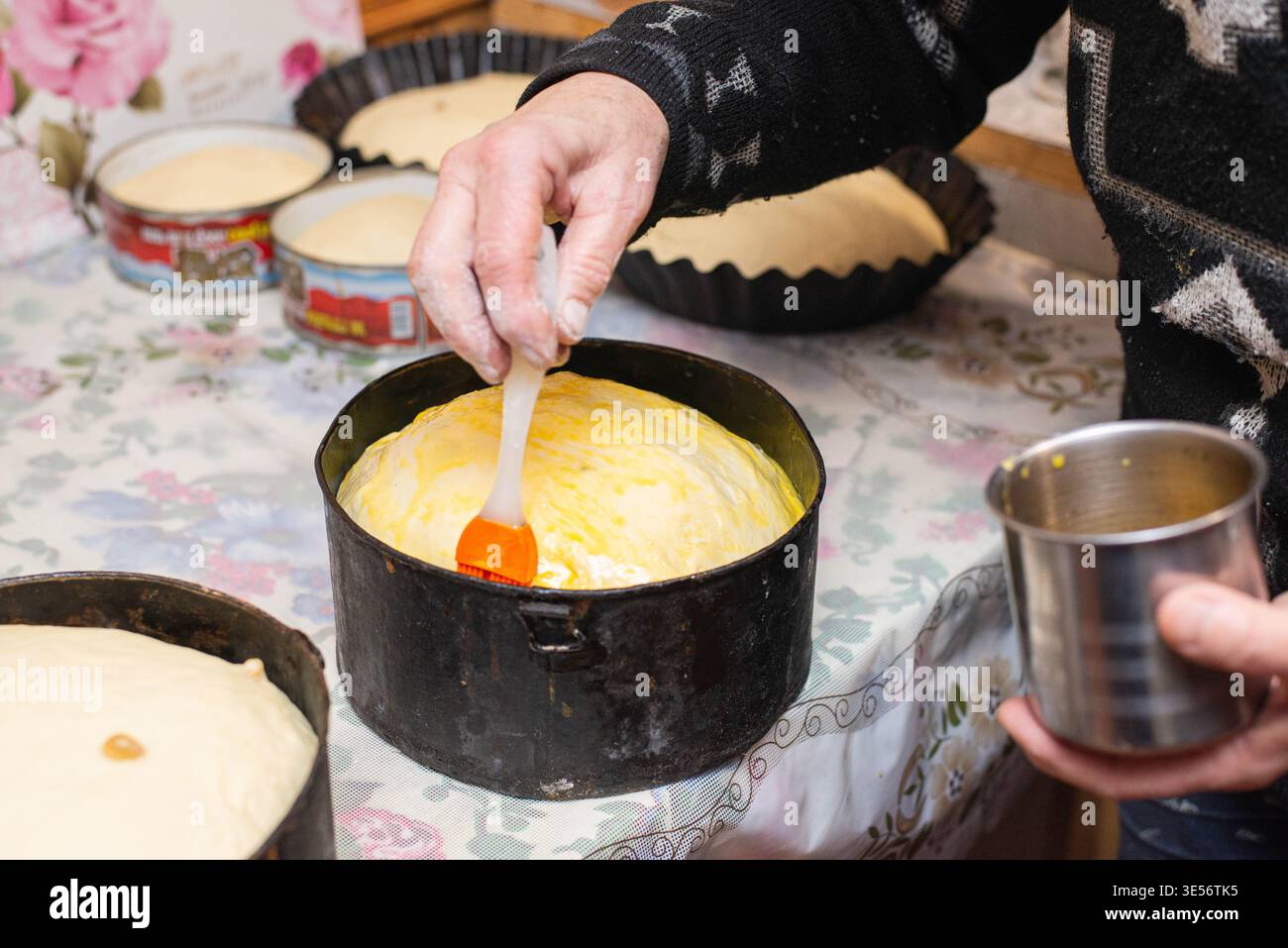 Nahaufnahme des Aufbringens von Eierwaschmittel auf traditionellen Osterbrotteig vor dem Backen. Hausgemachte Festvorbereitung für die Feiertagsfeier. Stockfoto