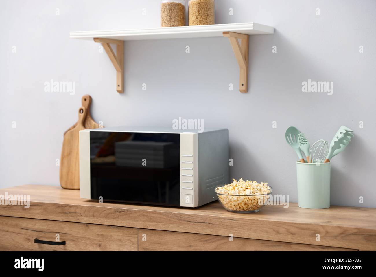 Moderne Mikrowelle und Popcorn-Schüssel auf der Theke in der Küche Stockfoto