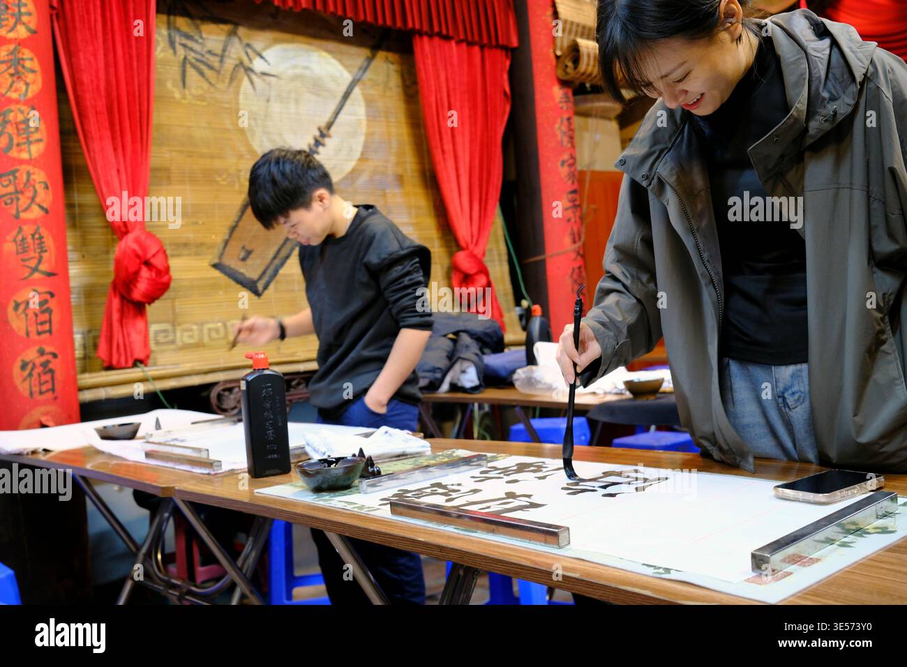Kalligraphie-Workshop-Szene mit zwei Teilnehmern, die mit Tintenbürsten auf Reispapier schreiben. Hanoi. Vietnam. Stockfoto