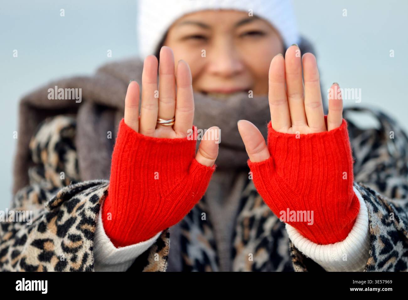 Elegante Dame zeigt Hände in gestrickten roten Fäustlingen und goldenem Band, Winterhaube auf ihrem lächelnden Ausdruck. Sopot. Polen. Stockfoto