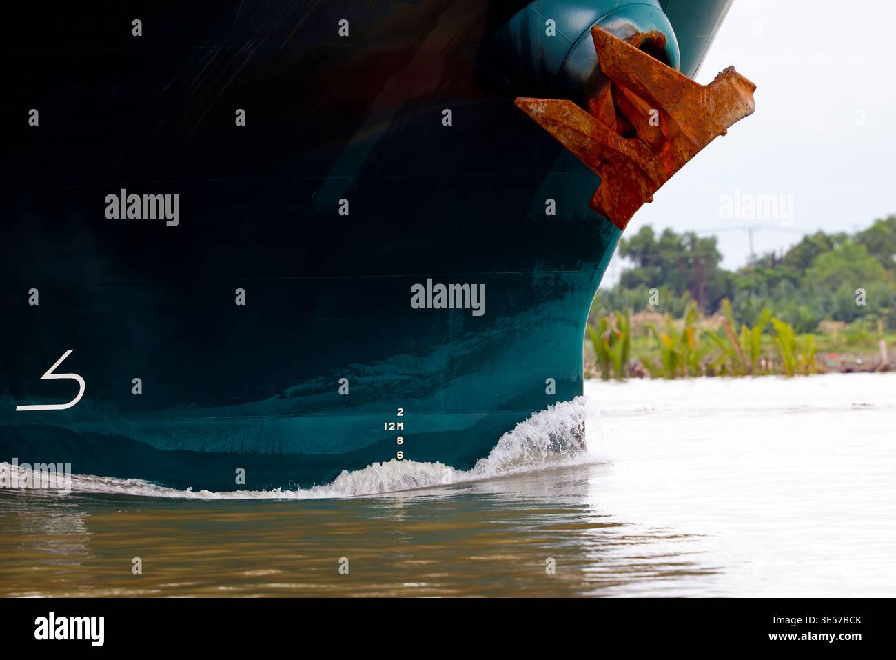 Nahaufnahme eines großen Frachtschiffbogens mit rostigem Anker, der einen tropischen Fluss navigiert. Vung Tau. Vietnam. Stockfoto