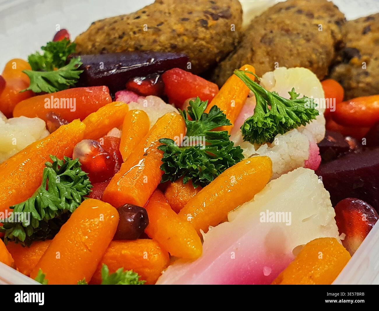 Ein Makrofoto aus Nahaufnahme einer bunten gesunden Mahlzeit, die in einem weißen Behälter serviert wird, mit glasierten BabyKarotten, in Scheiben geschnittenen violetten Rüben und weißen Rüben Stockfoto