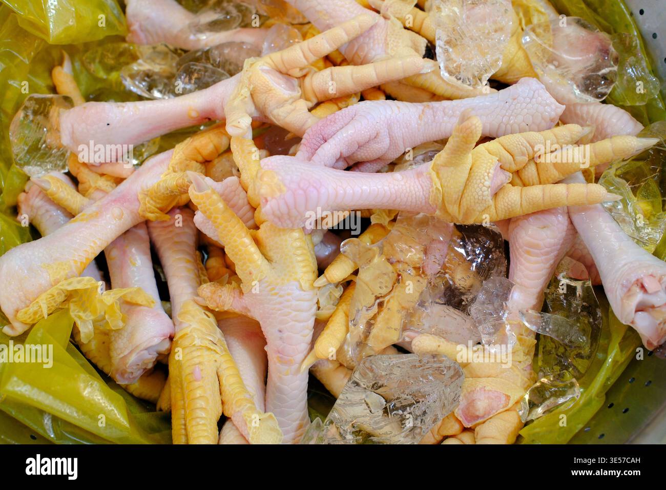 Frische, ungekochte Hähnchenfüße, die auf zerstoßenem Eis an einem nassen Marktstand gelagert werden. Vietnam. Stockfoto