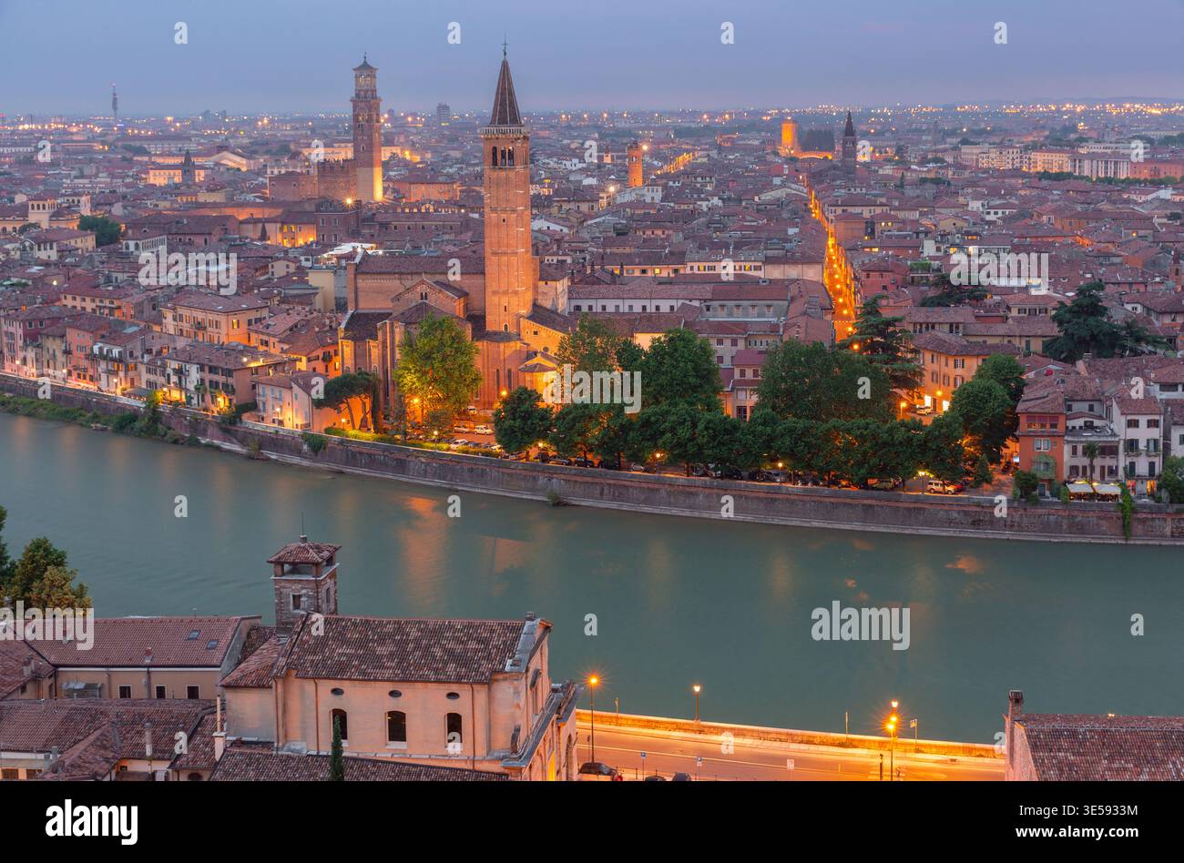 Panoramablick auf Verona mit der Etsch, historischen Kirchen und beleuchteten Straßen in der Abenddämmerung, Italien. Stockfoto