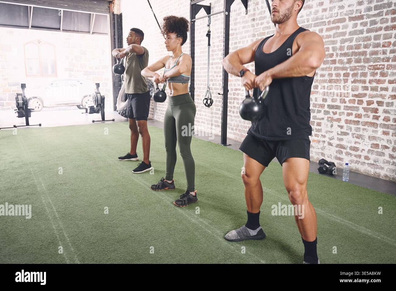 Kettlebells, Herausforderung und Menschen im Fitnessstudio, Fitness für gesundheitliche Vorteile und Wellness. Unterstützung, Männer und Frauen in der Einrichtung, Ausrüstung für Workout und Stockfoto