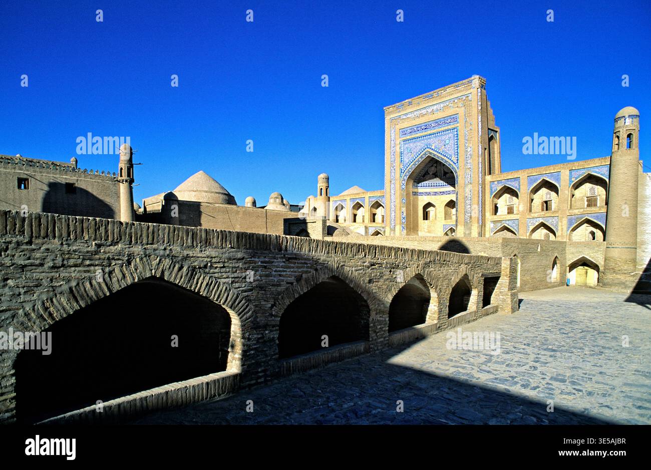 Menschen laufen durch die historischen Straßen von Chiwa und beobachten während des Tages einzigartige Gebäude und komplexe Designs. Stockfoto