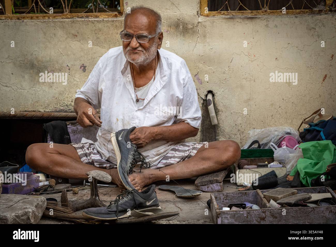 Ein älterer Mann repariert Schuhe auf den Straßen von Jaipur, Rajasthan, Indien Stockfoto