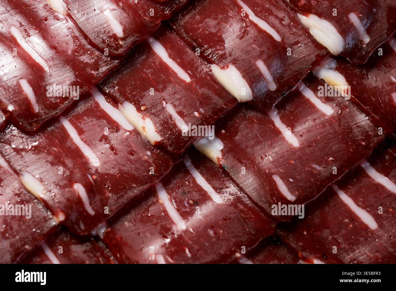 Dünne Schichten von Basturma glitzern im Licht, perfekt zum Teilen auf einem Festmahl. Stockfoto