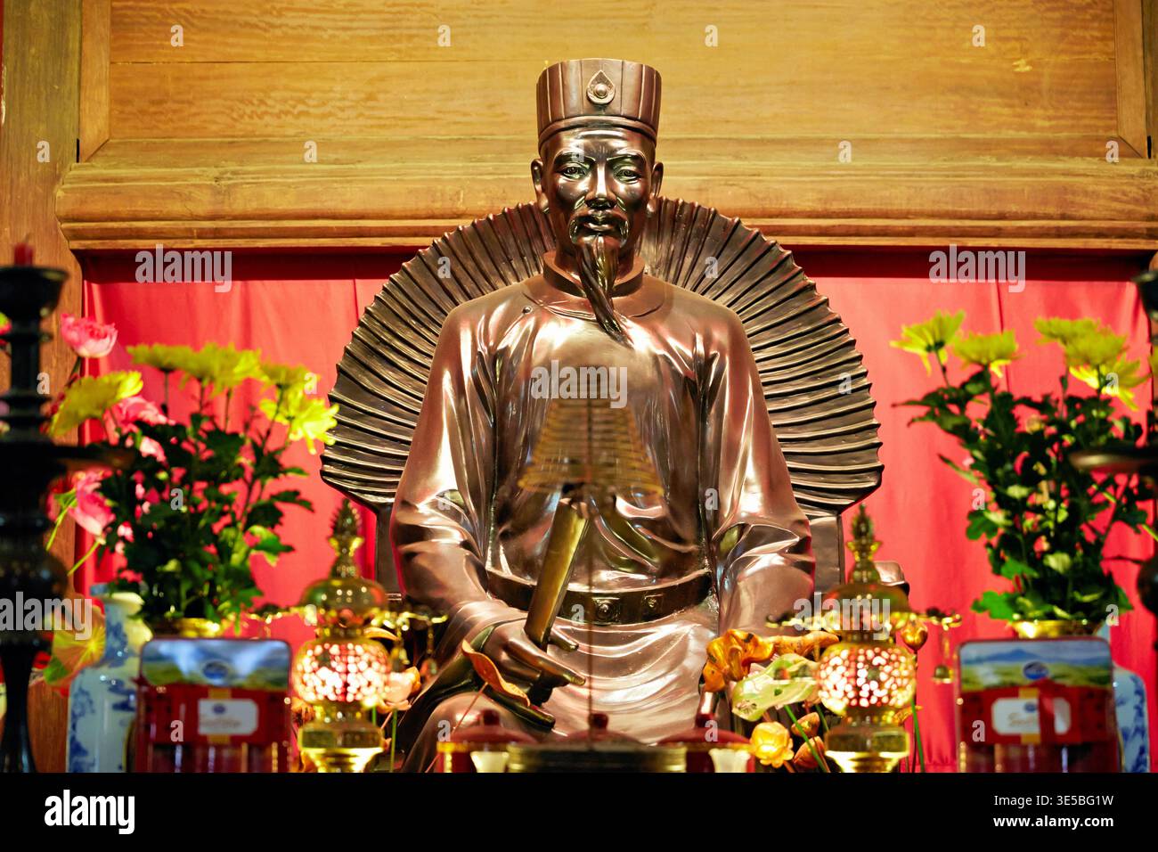 Eine Statue einer historischen Figur ist in einem Tempel in Hanoi ausgestellt. Blumen und Geschenke umgeben die Statue während eines lokalen Festivals. Stockfoto