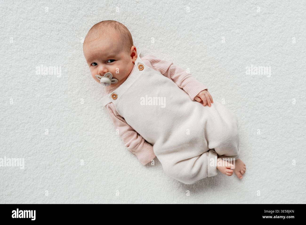 Säugling, der auf reinweißem Hintergrund in minimaler Art liegt. Einfaches und ästhetisches Babyporträt. Perfekt für Eltern, Gesundheit und Lebensstil Konzepte Stockfoto