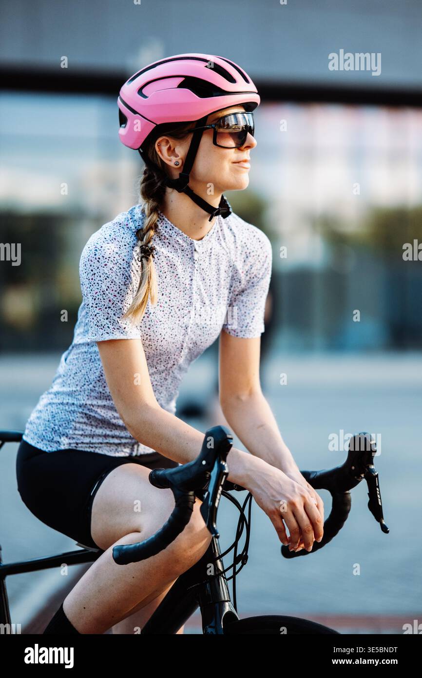 Lächelnde Frau Mit Bikewear. Entspannte Urbane Radfahrerin Zeigt Freundliche Einstellung Mit Geflochtenem Haar Stockfoto