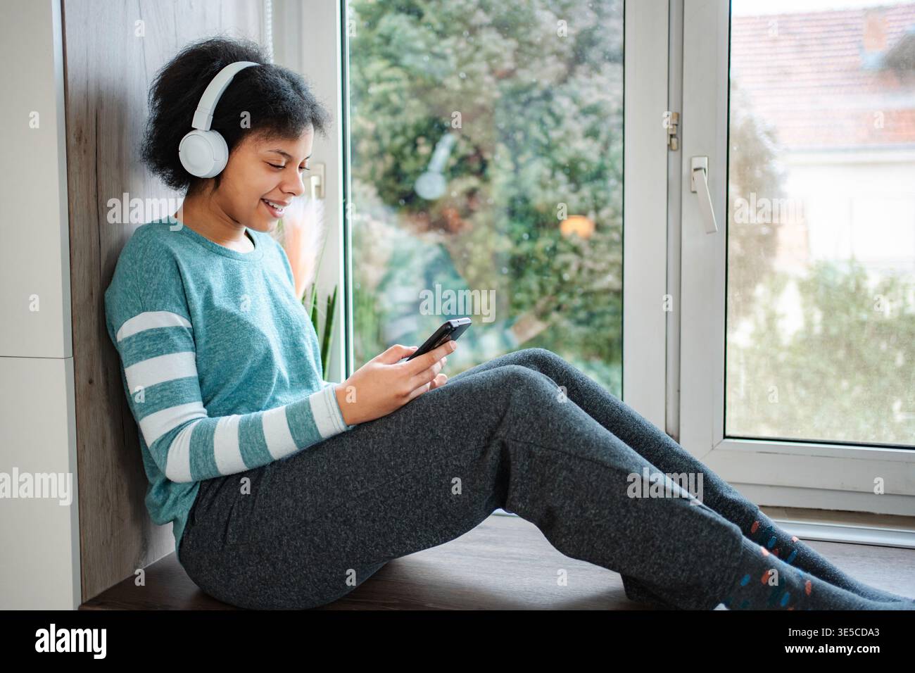 Junge Frau, die Musik über Kopfhörer mit dem Smartphone hört Stockfoto