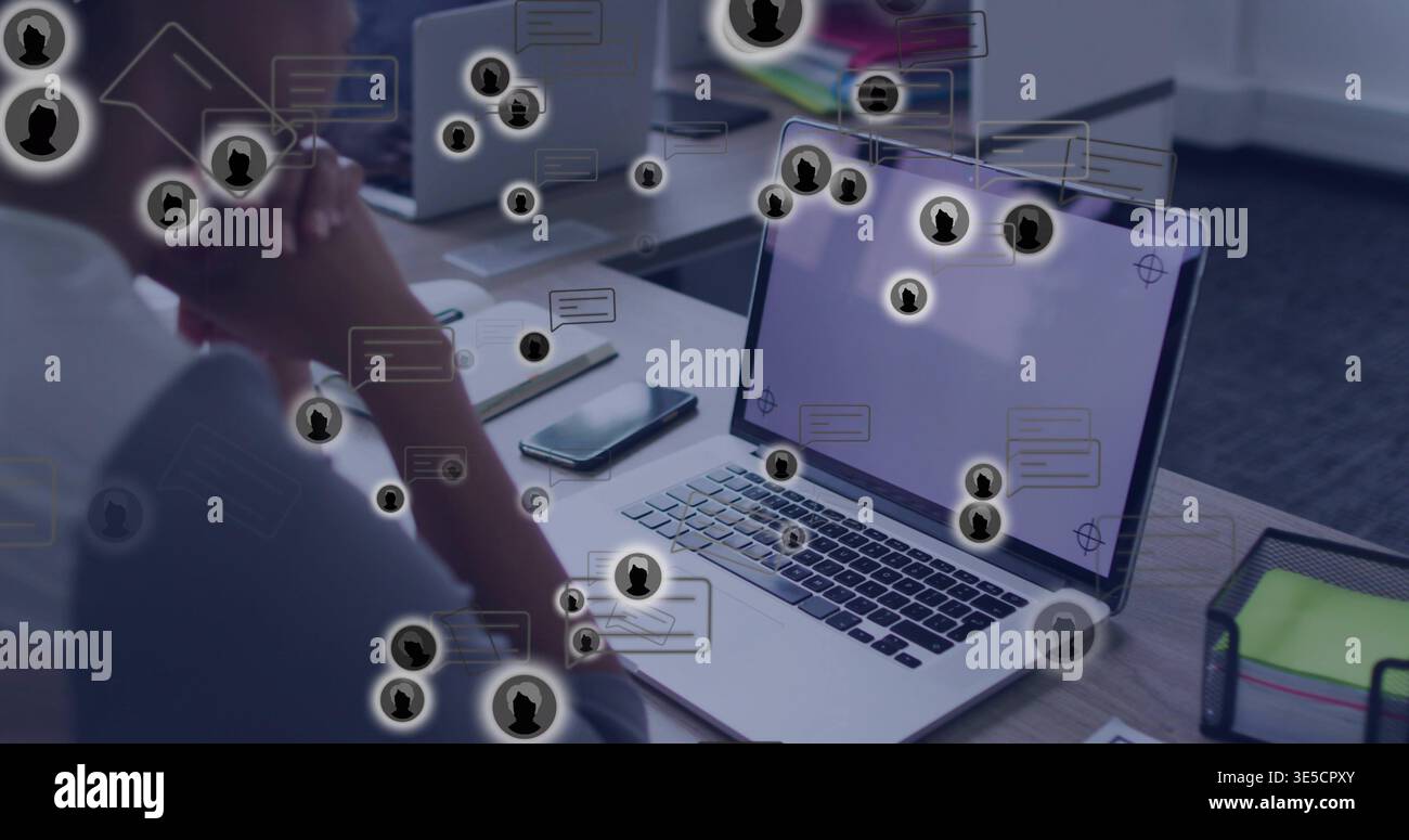 Zeigt offenen silbernen Laptop mit Chat-Overlays am gemeinsamen Schreibtisch, Telefon, Paar mit Arbeitskleidung Stockfoto