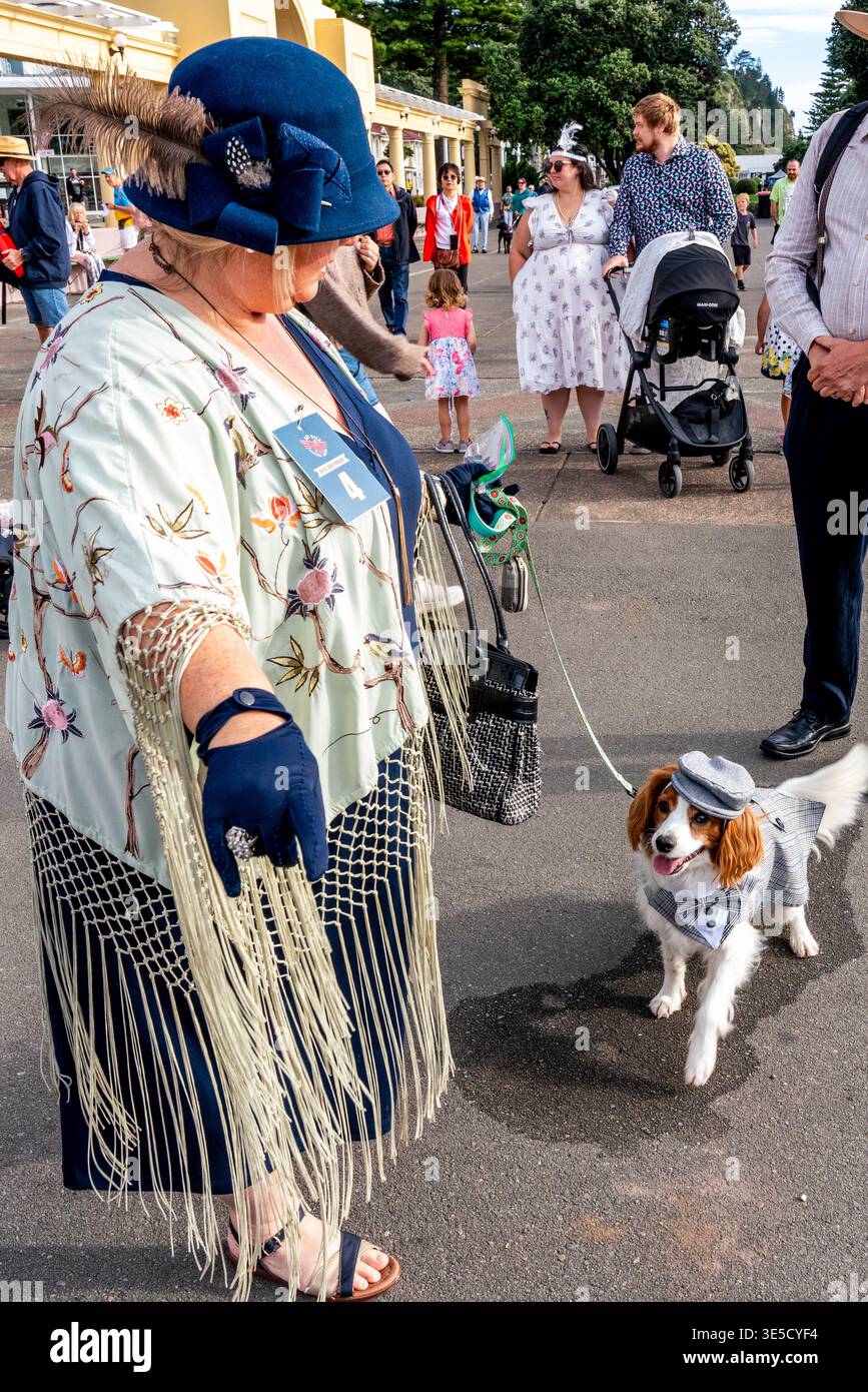Eine Frau im Art Deco Kostüm mit ihrem Haustier Hund wartet auf den Beginn der Deco Dog Parade, Napier Art Deco Festival, Napier, Hawke's Bay, Neuseeland Stockfoto