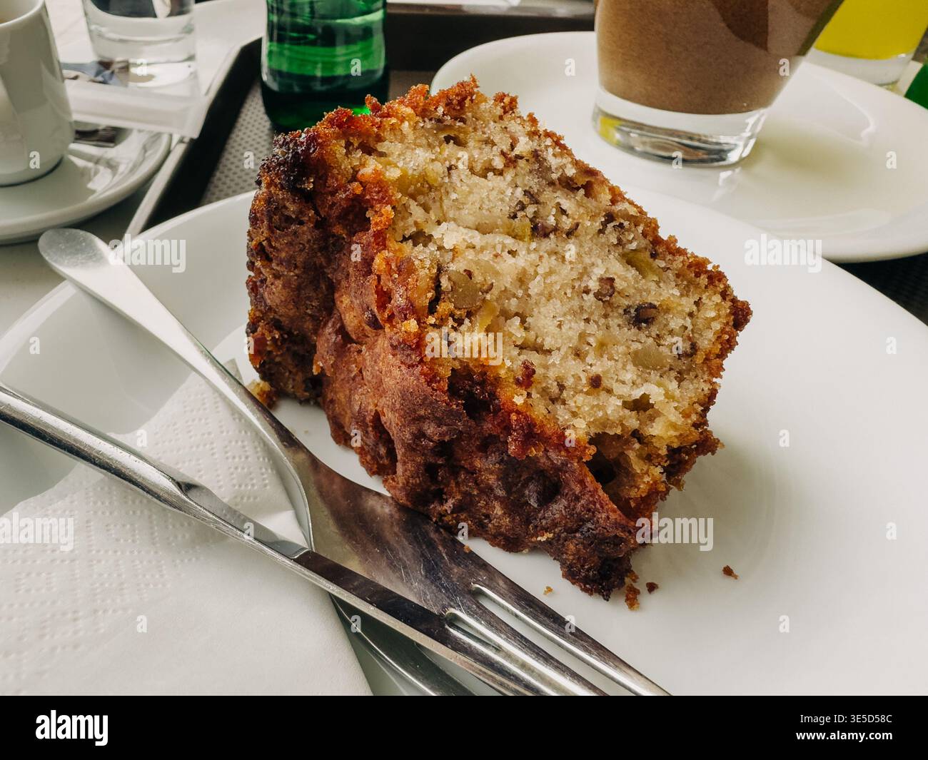 Ein verführerisches Stück feuchter Walnusskuchen wird elegant auf einem weißen Teller serviert und bietet ein verwöhnendes Schuldgefühl. Ideal für eine sinnliche Feier mit Stockfoto